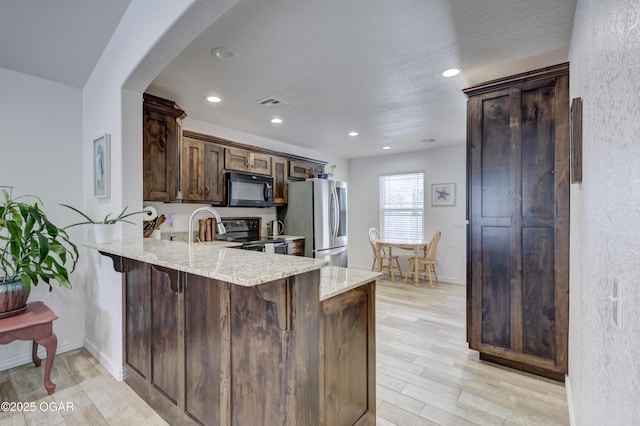 kitchen featuring range with electric cooktop, a kitchen bar, light wood-type flooring, kitchen peninsula, and stainless steel fridge