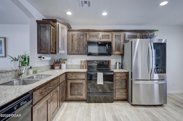 kitchen with light stone counters, sink, light hardwood / wood-style floors, black appliances, and dark brown cabinetry