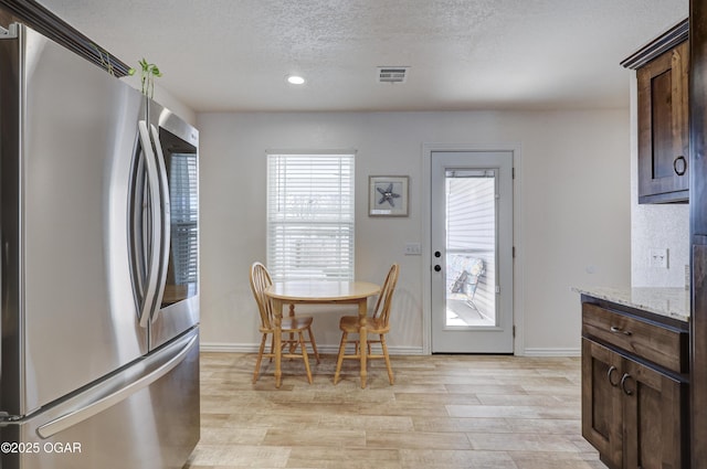 dining area with a textured ceiling and light hardwood / wood-style flooring