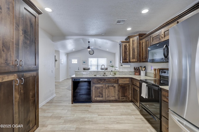 kitchen with kitchen peninsula, vaulted ceiling, light hardwood / wood-style flooring, black appliances, and sink