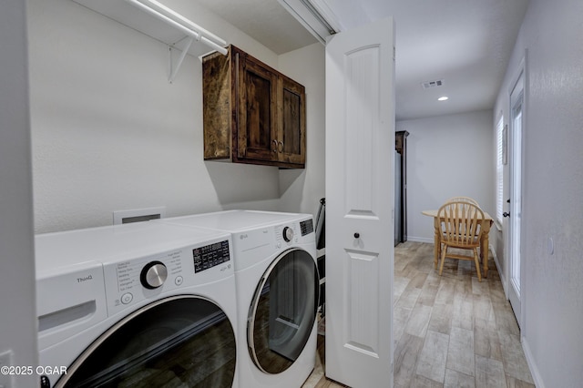 laundry room featuring cabinets, washer and clothes dryer, and light wood-type flooring