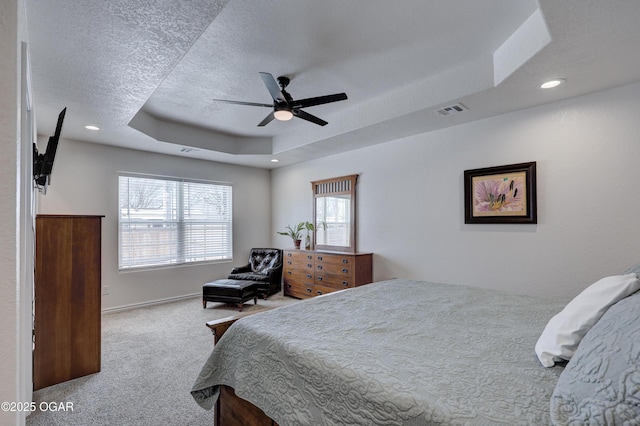 carpeted bedroom featuring a raised ceiling, ceiling fan, and a textured ceiling