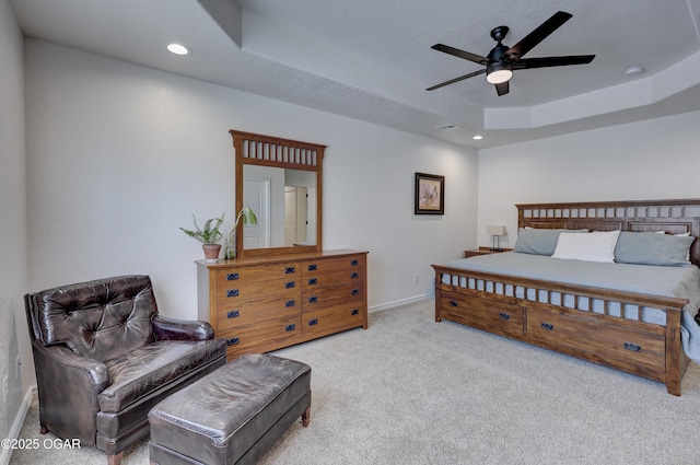 bedroom featuring ceiling fan, a tray ceiling, and light colored carpet