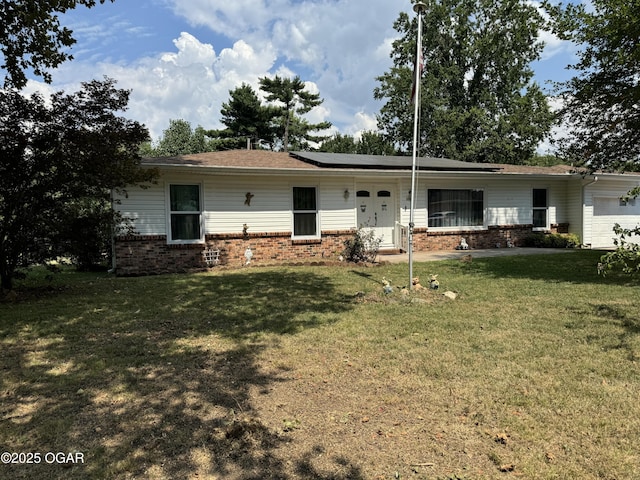 back of property with a lawn, a garage, and solar panels