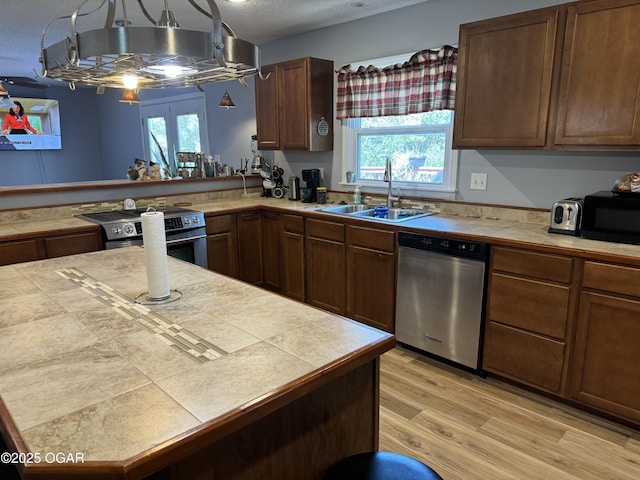 1019 Hawthorne St, Carthage, MO 64836 - kitchen with appliances with stainless steel finishes, healthy amount of natural light, light wood-style floors, a textured ceiling, and tile counters