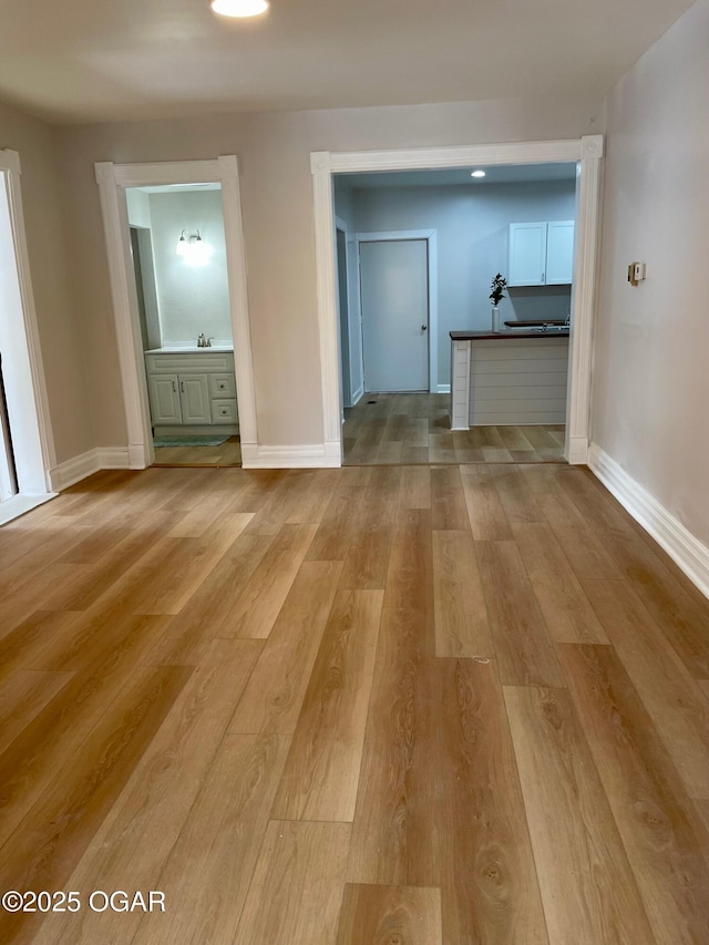 interior space featuring light wood finished floors, a sink, and baseboards