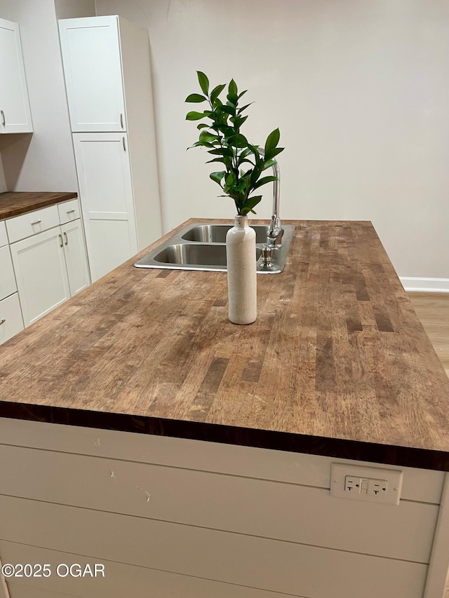 room details with butcher block countertops, white cabinets, and a sink