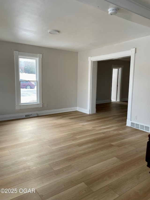 unfurnished room with light wood finished floors, baseboards, and visible vents