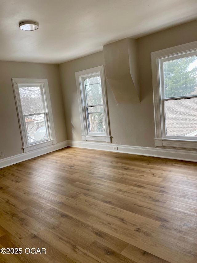 unfurnished room featuring baseboards, plenty of natural light, and light wood-style floors