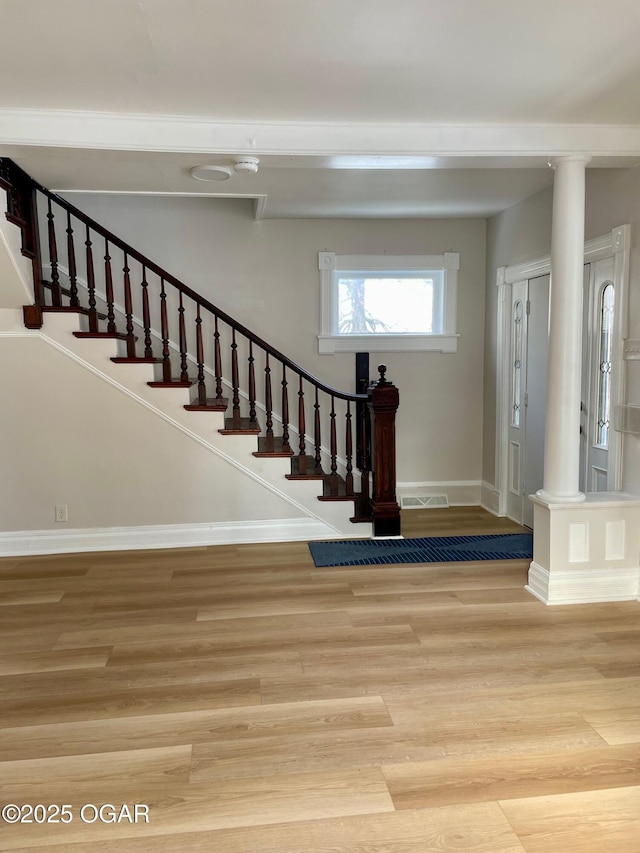 entryway featuring visible vents, baseboards, light wood-style floors, stairway, and decorative columns