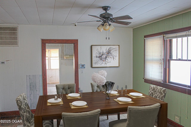 dining space with wooden walls and ceiling fan