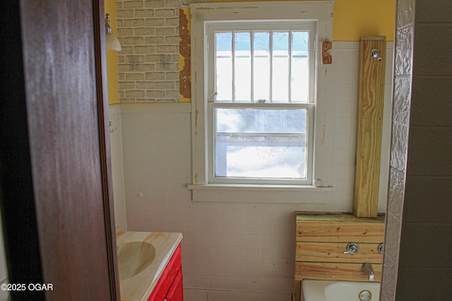 bathroom with vanity, tile walls, and a tub to relax in