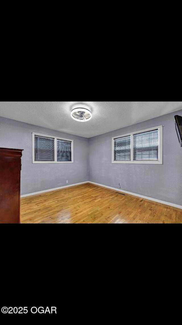 empty room featuring a textured ceiling and light hardwood / wood-style floors