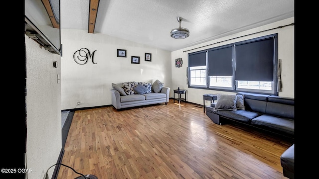 living room with a textured ceiling, lofted ceiling with beams, and wood-type flooring