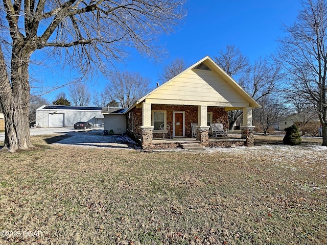 view of front of home featuring a porch, a garage, and a front lawn