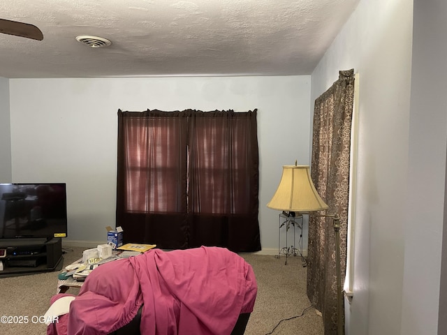 bedroom with ceiling fan, light colored carpet, and a textured ceiling