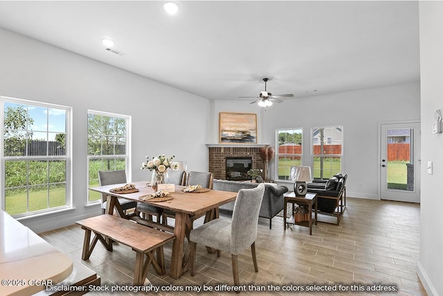 dining room with a brick fireplace and ceiling fan