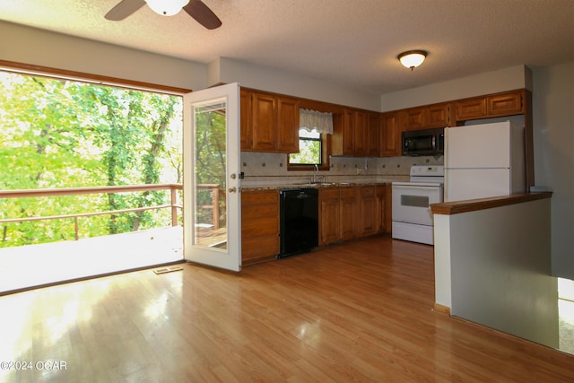 kitchen featuring white appliances, a textured ceiling, light wood-type flooring, and sink