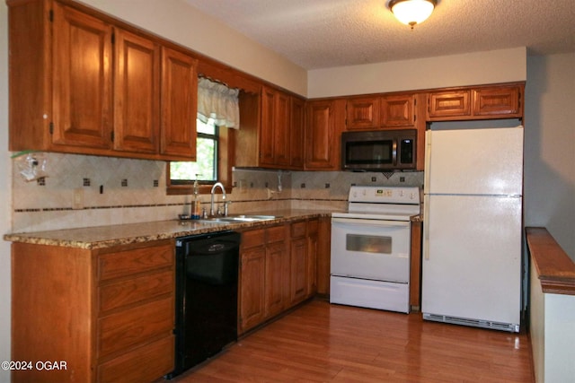 kitchen with white appliances, a textured ceiling, light hardwood / wood-style flooring, backsplash, and sink