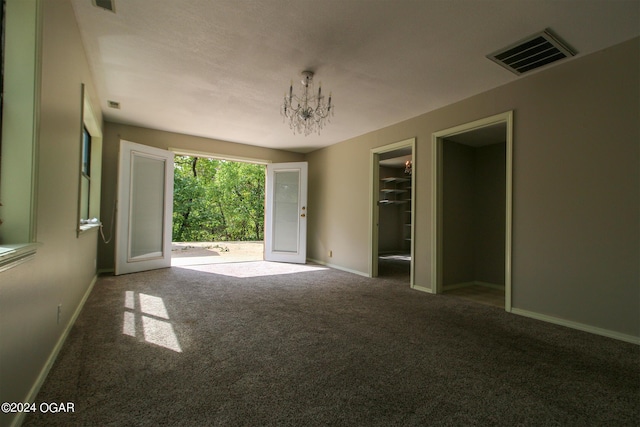 carpeted empty room featuring a chandelier