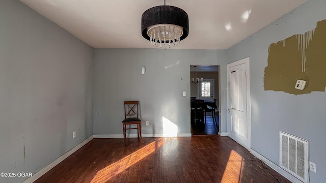 empty room featuring dark hardwood / wood-style flooring and an inviting chandelier