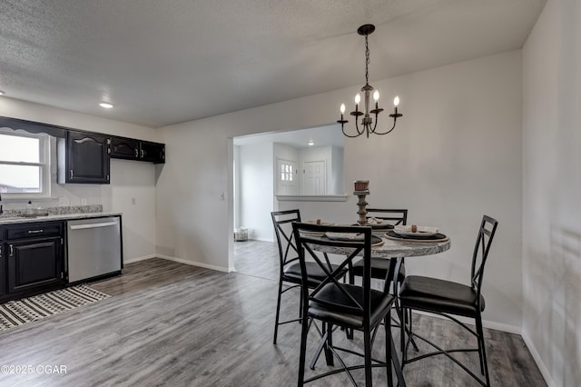 dining area with a textured ceiling, light hardwood / wood-style flooring, and a notable chandelier