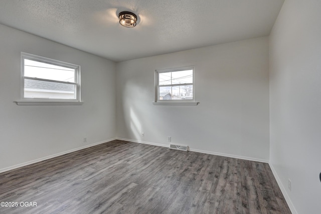 empty room with dark hardwood / wood-style flooring and a textured ceiling