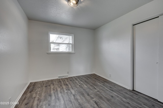 unfurnished room with hardwood / wood-style floors and a textured ceiling