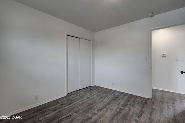 unfurnished bedroom with dark hardwood / wood-style flooring and a closet