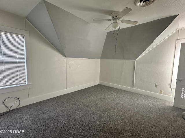 additional living space with lofted ceiling, dark carpet, and ceiling fan