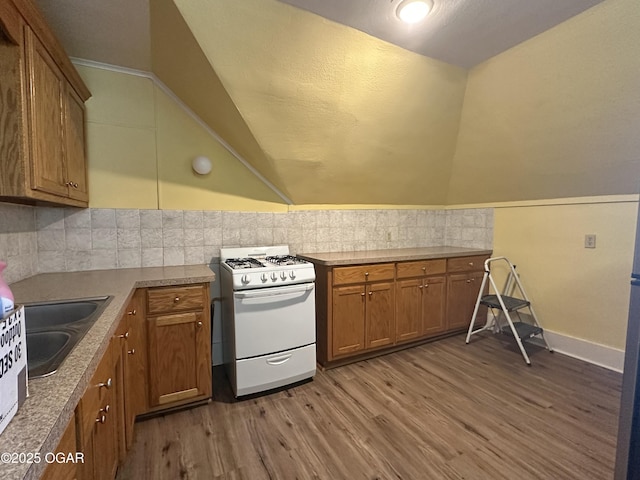 kitchen featuring tasteful backsplash, wood-type flooring, vaulted ceiling, and white gas stove