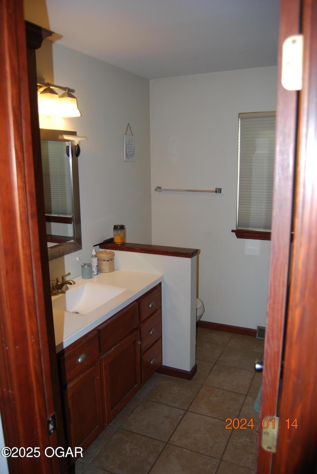 bathroom with toilet, vanity, and tile patterned flooring