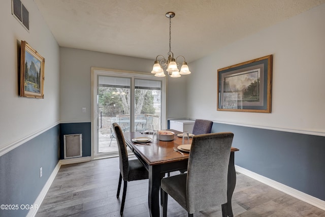 dining area featuring wood-type flooring and a notable chandelier