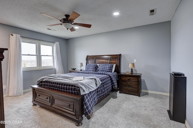 bedroom with ceiling fan, light colored carpet, and a textured ceiling