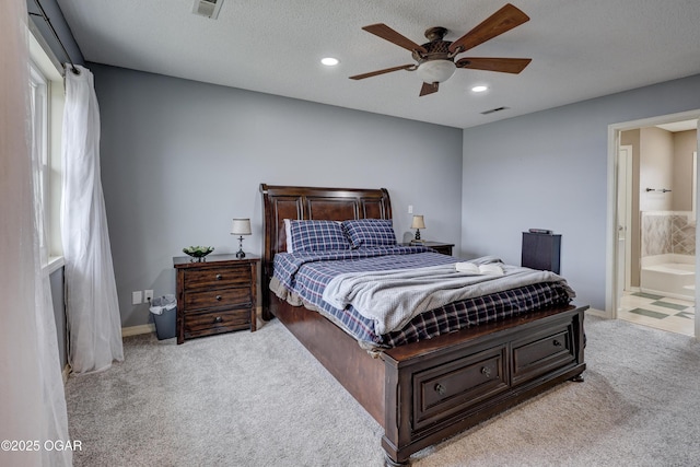 bedroom with ensuite bathroom, light carpet, ceiling fan, and a textured ceiling