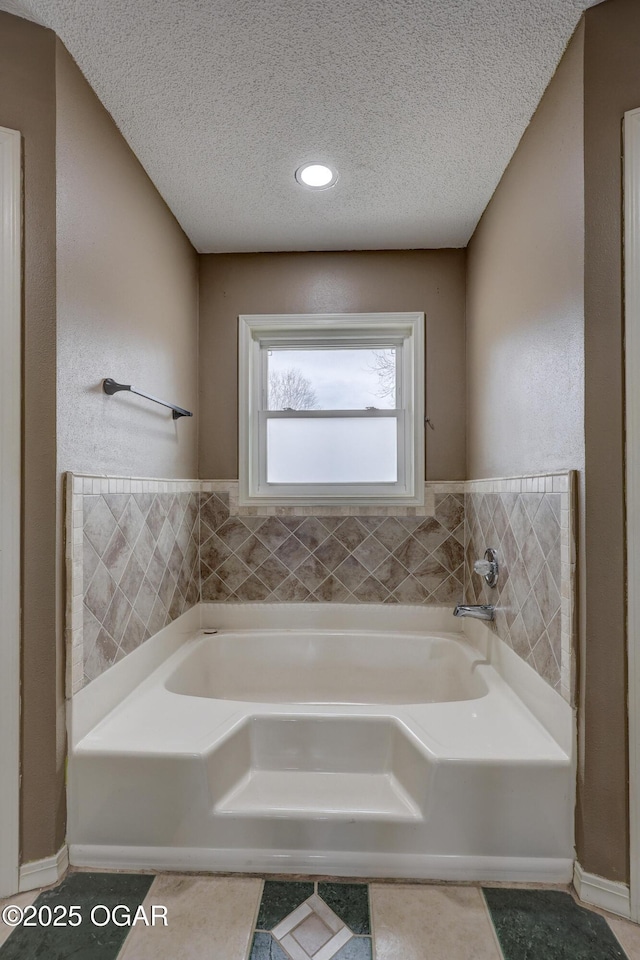 bathroom featuring tile patterned flooring, a bath, and a textured ceiling