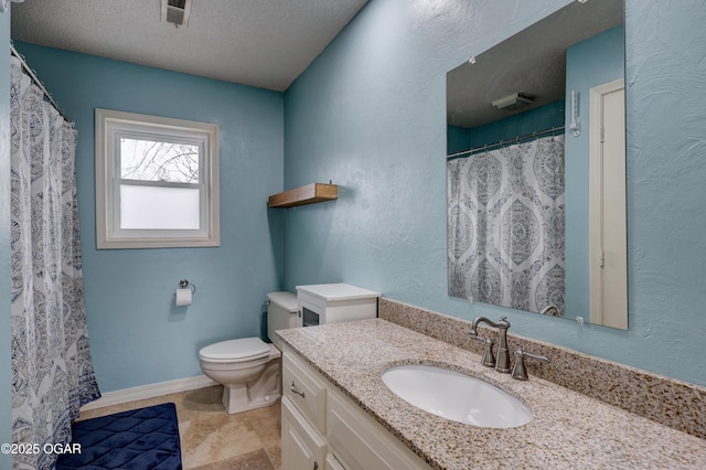 bathroom with vanity, toilet, and a textured ceiling