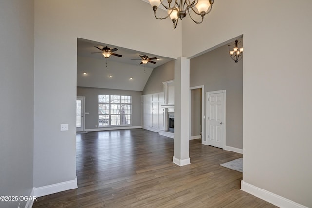 unfurnished living room with high vaulted ceiling, wood-type flooring, and ceiling fan with notable chandelier