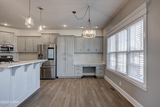 kitchen featuring decorative light fixtures, backsplash, gray cabinets, and stainless steel appliances