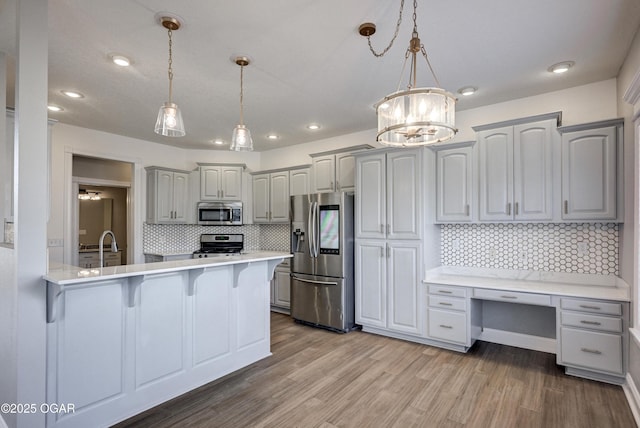 kitchen with decorative backsplash, hanging light fixtures, gray cabinets, and stainless steel appliances