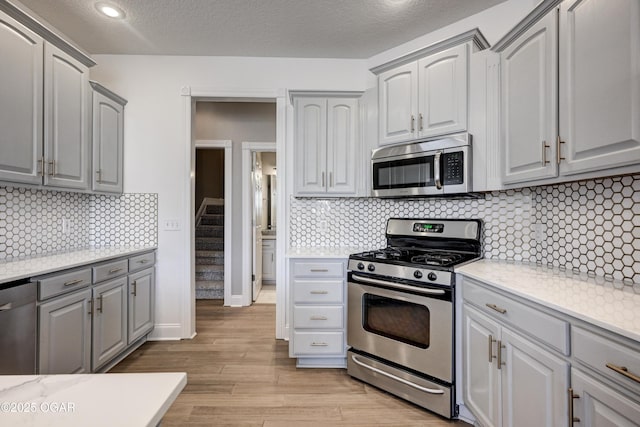 kitchen with appliances with stainless steel finishes, decorative backsplash, and gray cabinets