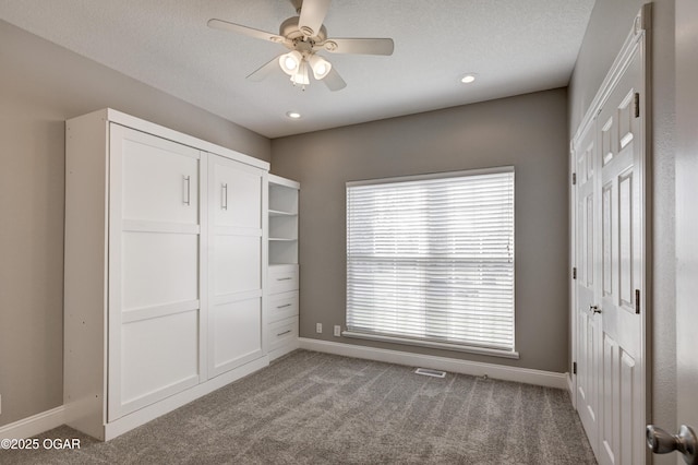 unfurnished bedroom with ceiling fan, multiple windows, and carpet flooring