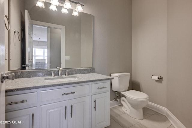 bathroom with toilet, vanity, and tile patterned flooring