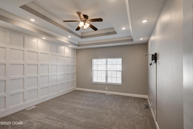 unfurnished room featuring ceiling fan, carpet flooring, and a tray ceiling