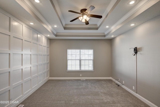 carpeted empty room featuring ceiling fan, crown molding, and a raised ceiling