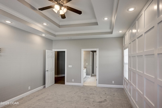 unfurnished bedroom with ceiling fan, crown molding, a tray ceiling, and light carpet