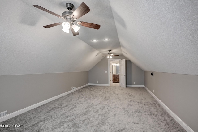 additional living space featuring ceiling fan, light colored carpet, a textured ceiling, and lofted ceiling