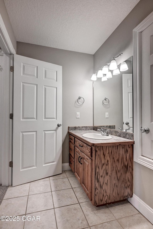 bathroom with a textured ceiling, vanity, and tile patterned flooring