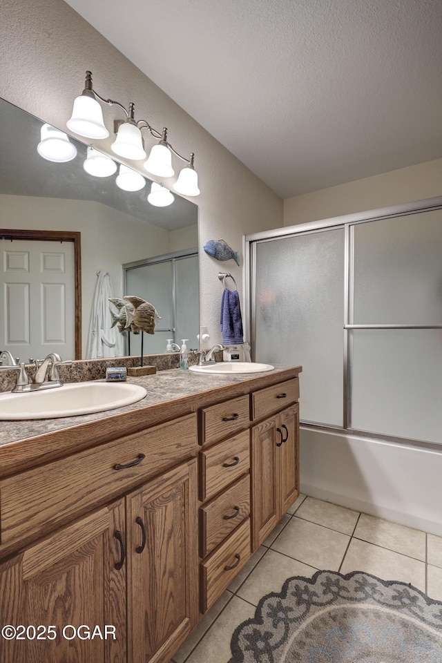 bathroom featuring a textured ceiling, vanity, bath / shower combo with glass door, and tile patterned floors