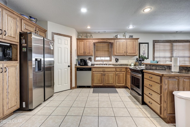 kitchen with sink, a textured ceiling, light tile patterned floors, and appliances with stainless steel finishes